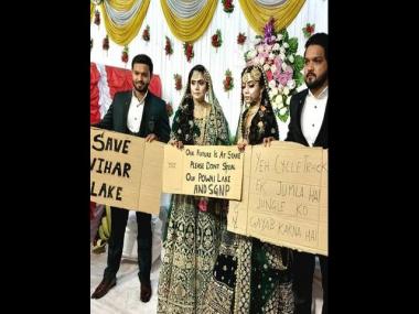 Two newly-married couples hold placards to protest against BMC cycle track